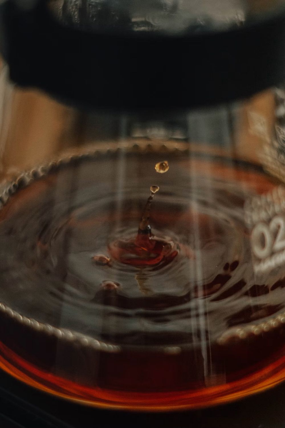 A drop of brewed coffee falling into a glass carafe