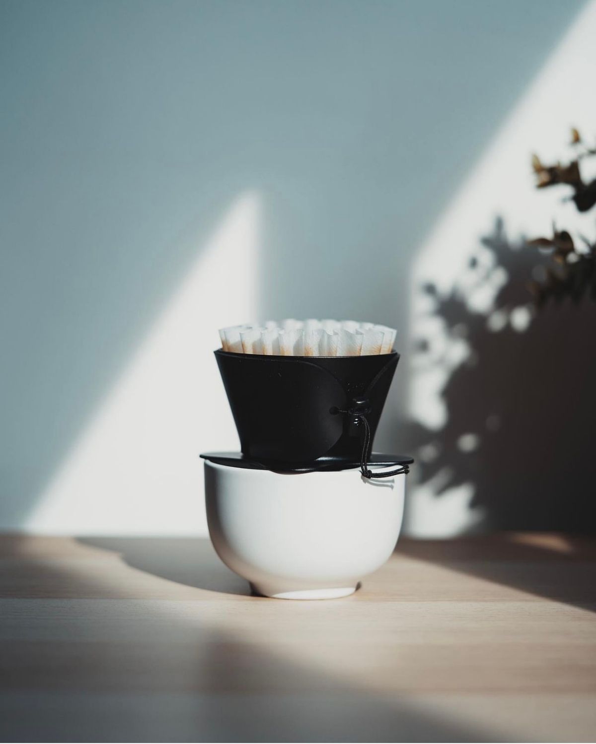 A pour-over dripper with a paper filter on a white cup, in morning light
