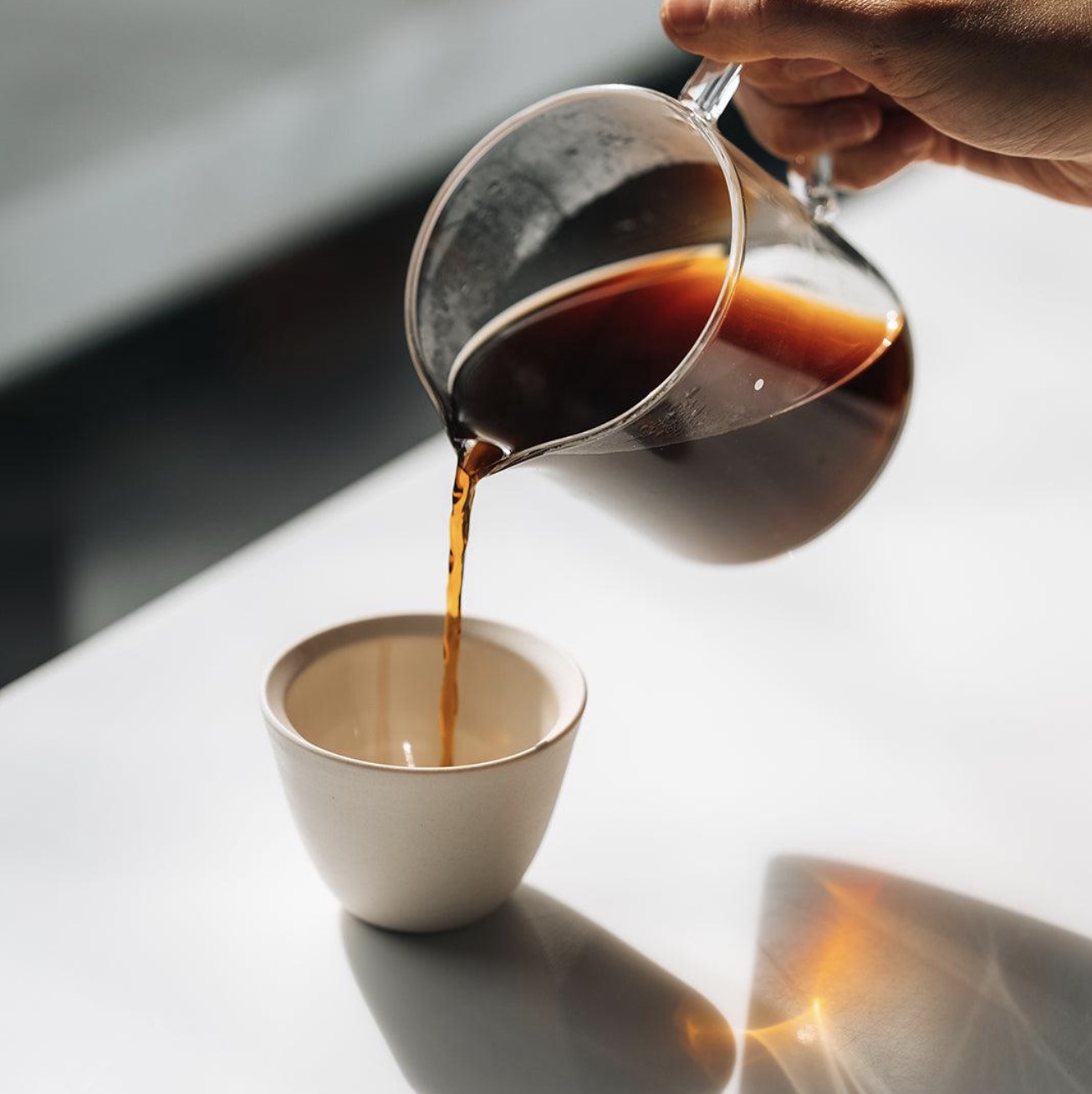Filter coffee poured from a glass carafe into a ceramic cup