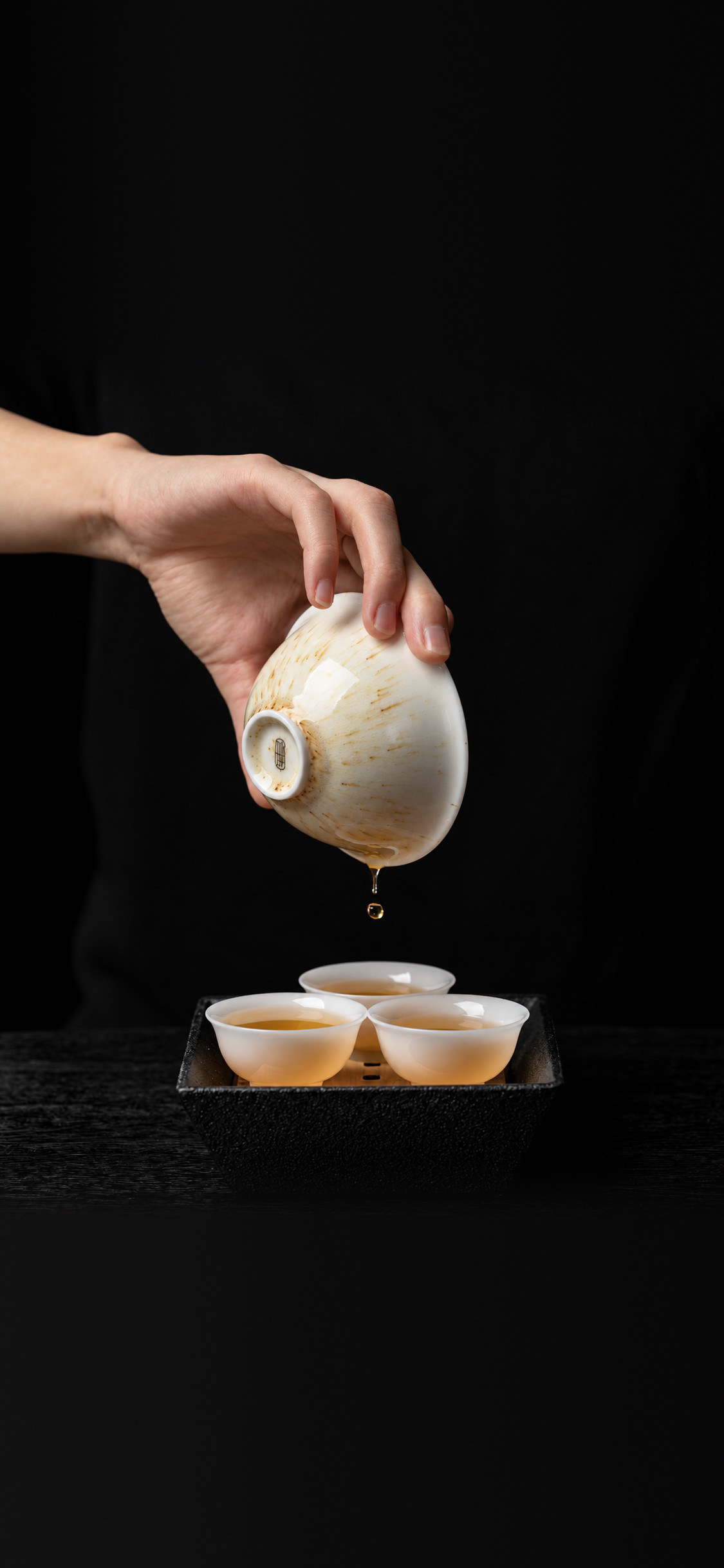 Tea poured from a gaiwan into three small cups