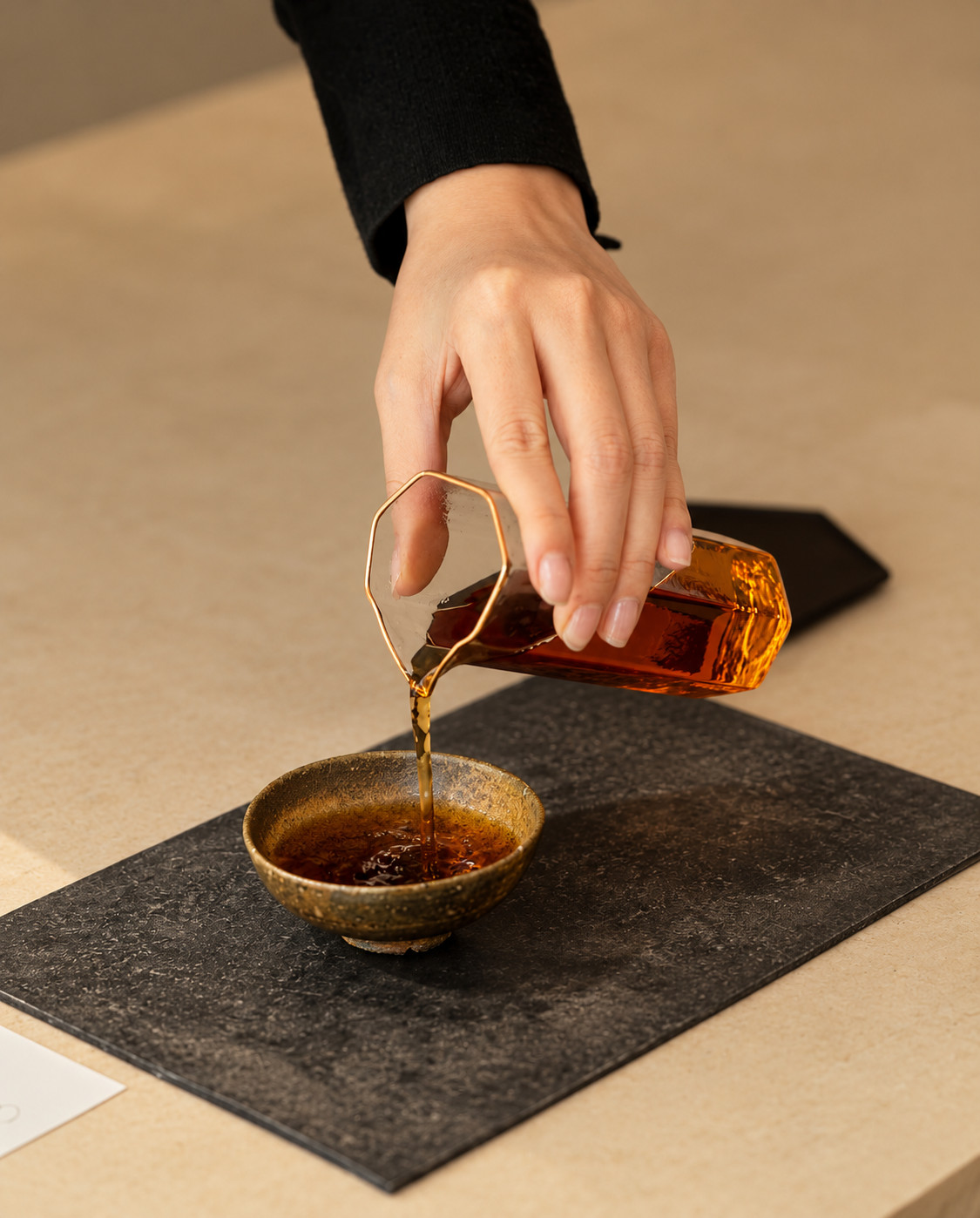 Tea poured from a glass pitcher into a cup